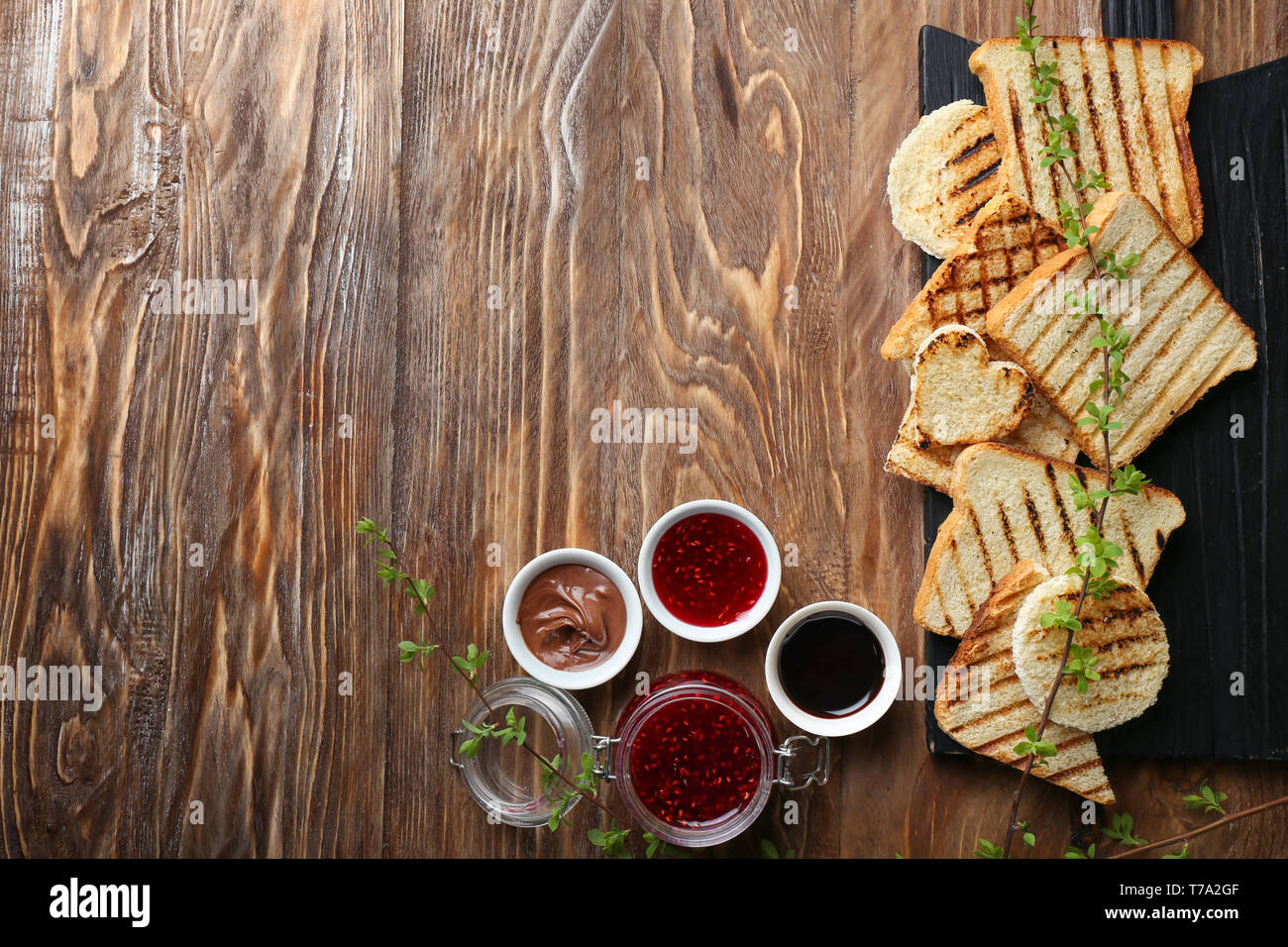 Toasted bread with sweet jam and chocolate paste on wooden table Stock ...