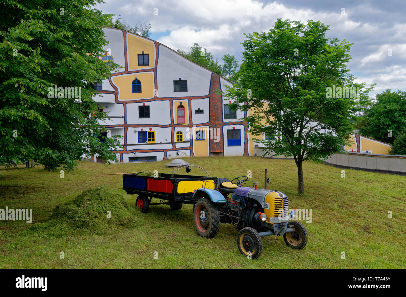 Colourful painted tractor and grass clippings in front of building at Rogner Bad Blumau, a resort or spa hotel designed by Friedensreich Hundertwasser Stock Photo