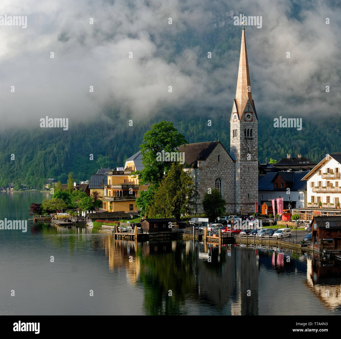 Early morning shot of the Evangelical Church of Hallstatt (Evangelische Pfarrkirche Hallstatt) and a lake reflection with low cloud in the background Stock Photo