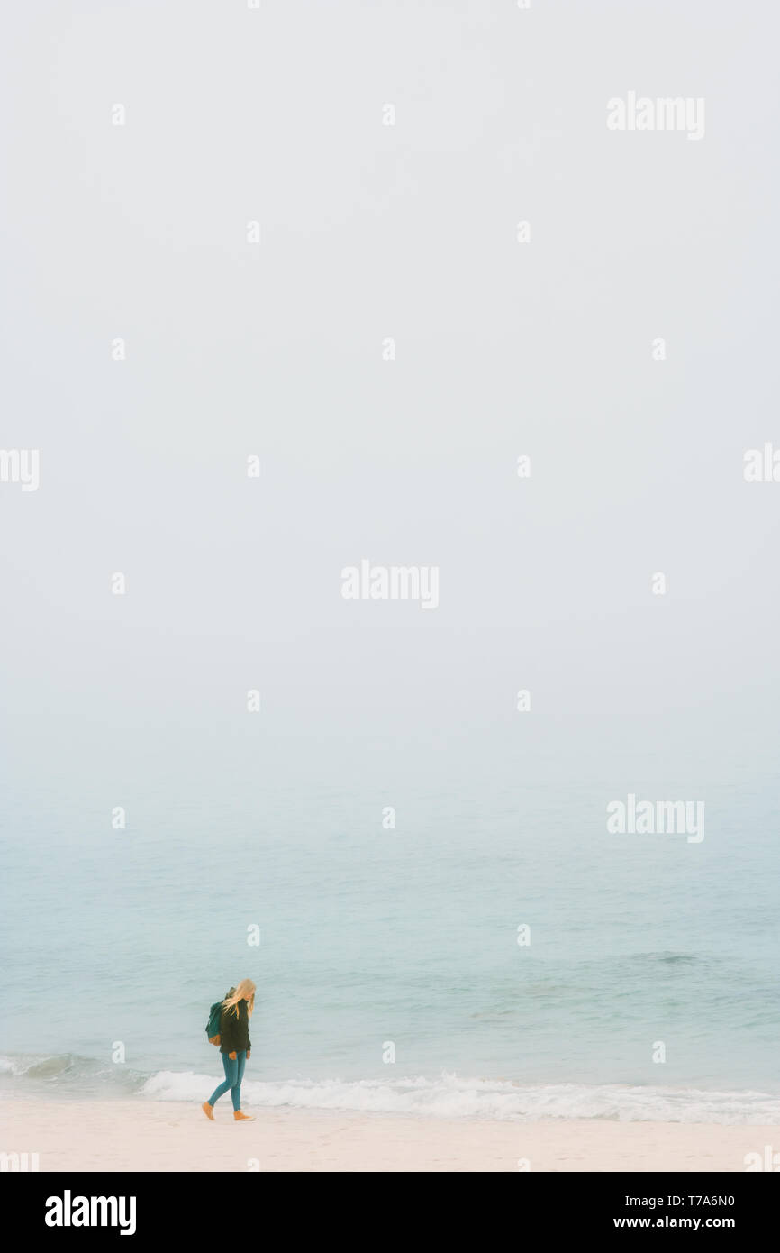Traveler girl walking alone on foggy beach Travel Lifestyle adventure outdoor minimal style Stock Photo