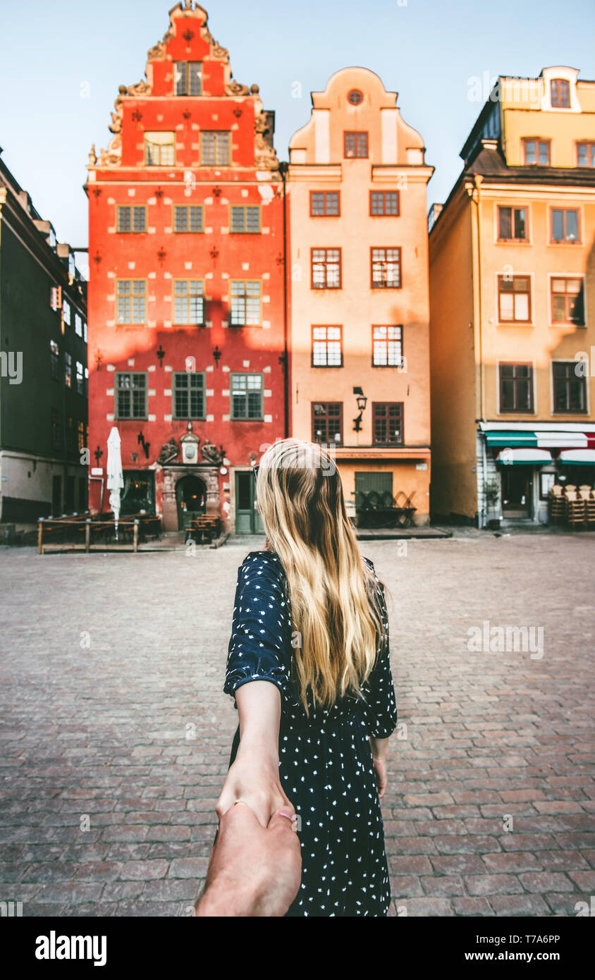 Couple follow holding hands traveling together in Stockholm sightseeing walk  vacations lifestyle Stortorget architecture Sweden landmarks Stock Photo
