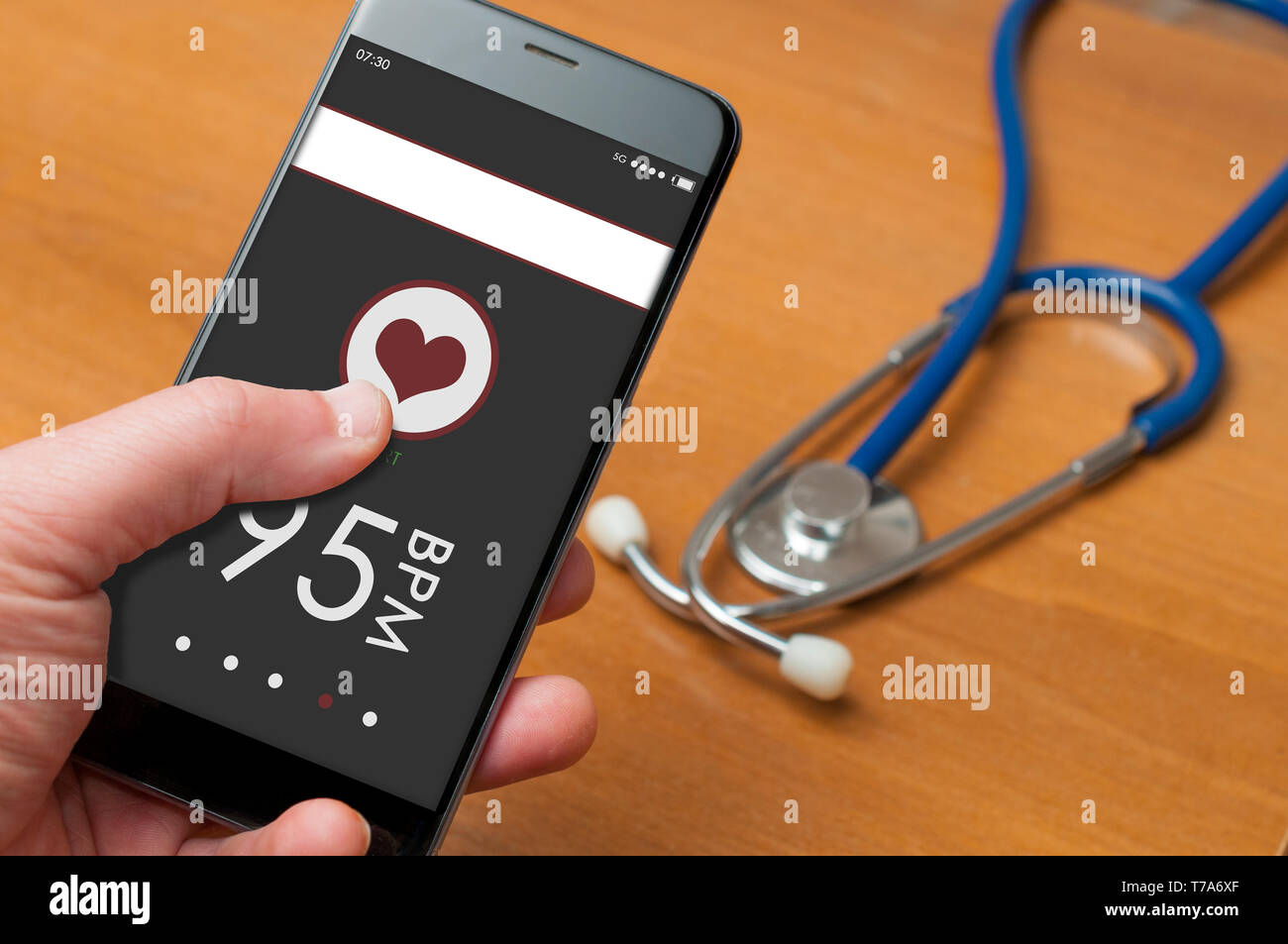 Man holding a smartphone with app for heart bpm measuring in front of a  desktop with a stethoscope Stock Photo - Alamy