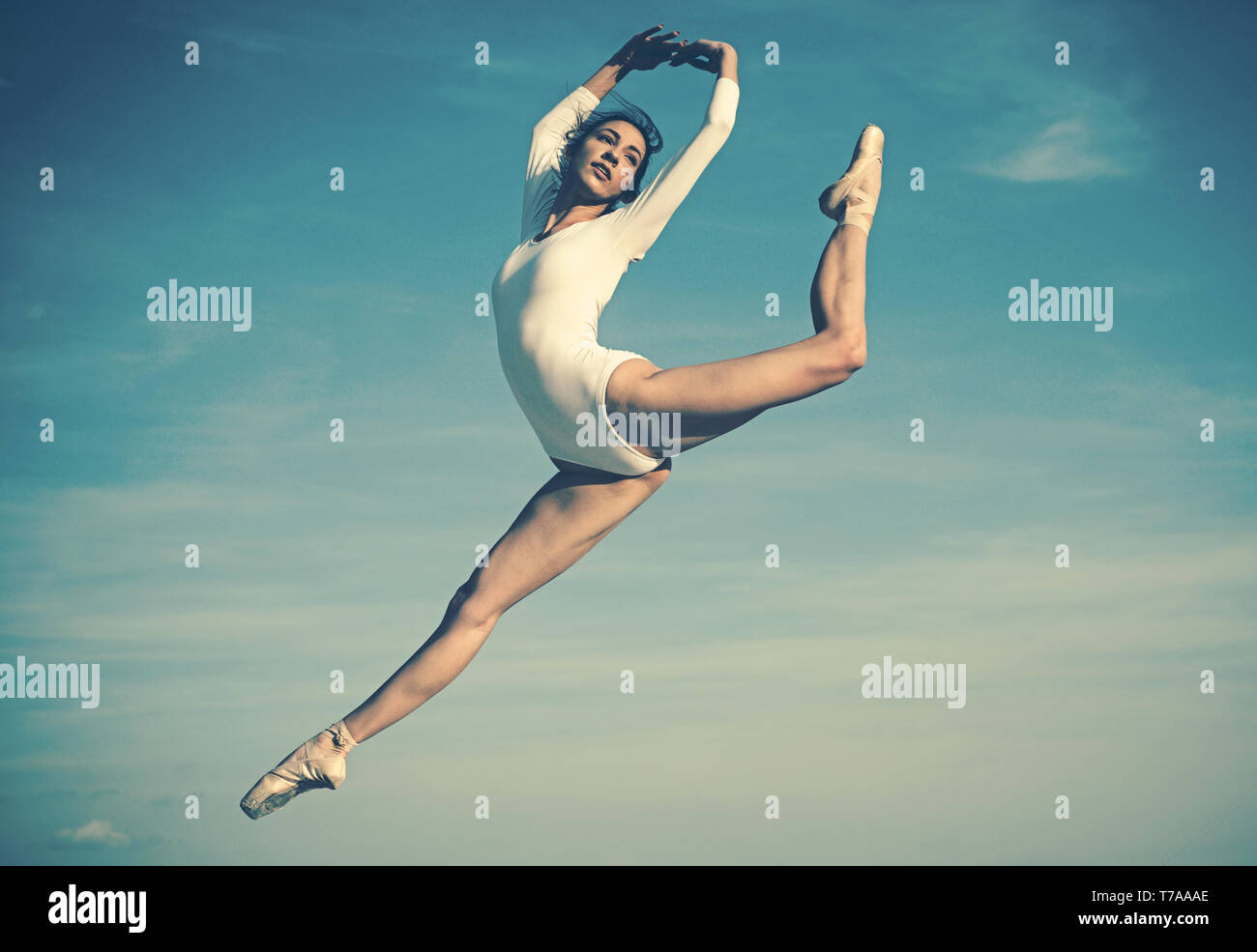 Practicing the art of classical ballet. Young ballerina jumping on blue sky. Pretty woman in dance wear. Cute ballet dancer. Concert performance dance Stock Photo