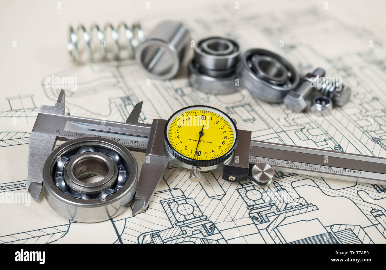 Accurate caliper gauge. Ball bearings diameter. Technical drafting. Analog metal measuring instrument and yellow round dial. Group of steel components. Stock Photo