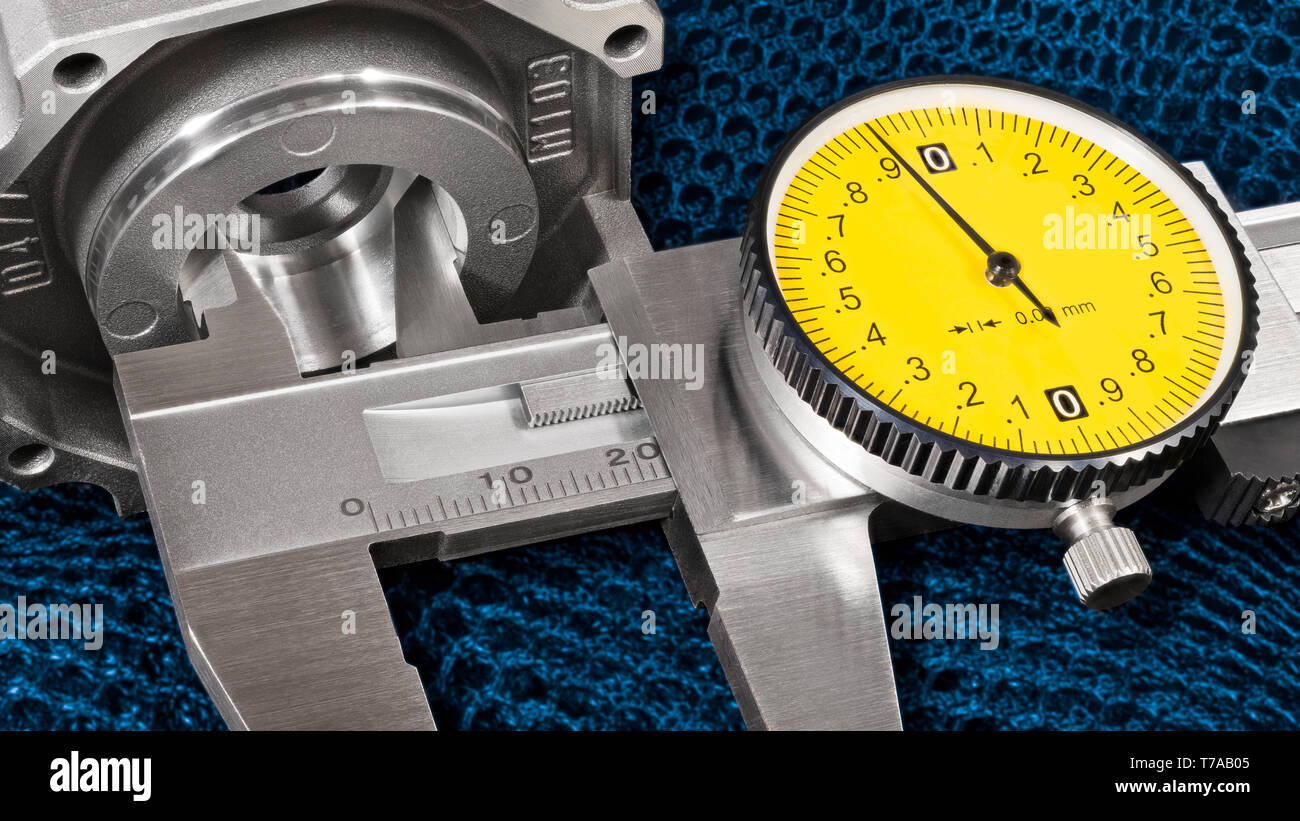 Internal hole diameter measurement. Caliper jaws detail. Aluminum cast of bearing housing. Vernier measuring instrument. Round yellow dial. Blue mesh. Stock Photo