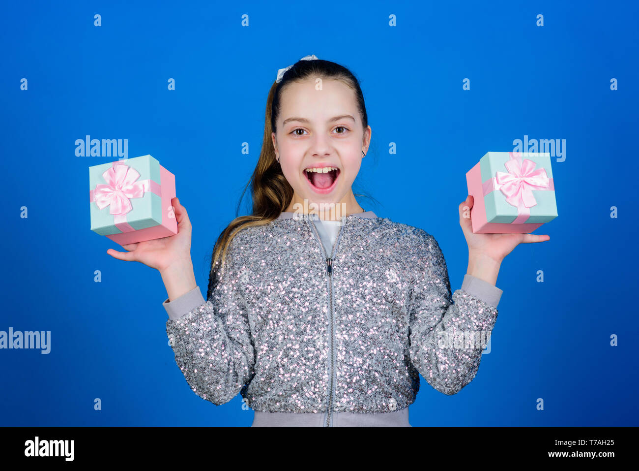 Girl with gift boxes blue background. Black friday. Shopping day. Cute child carry gift boxes. Surprise gift box. Birthday wish list. World of happiness. Pick bonus. Special happens every day. Stock Photo
