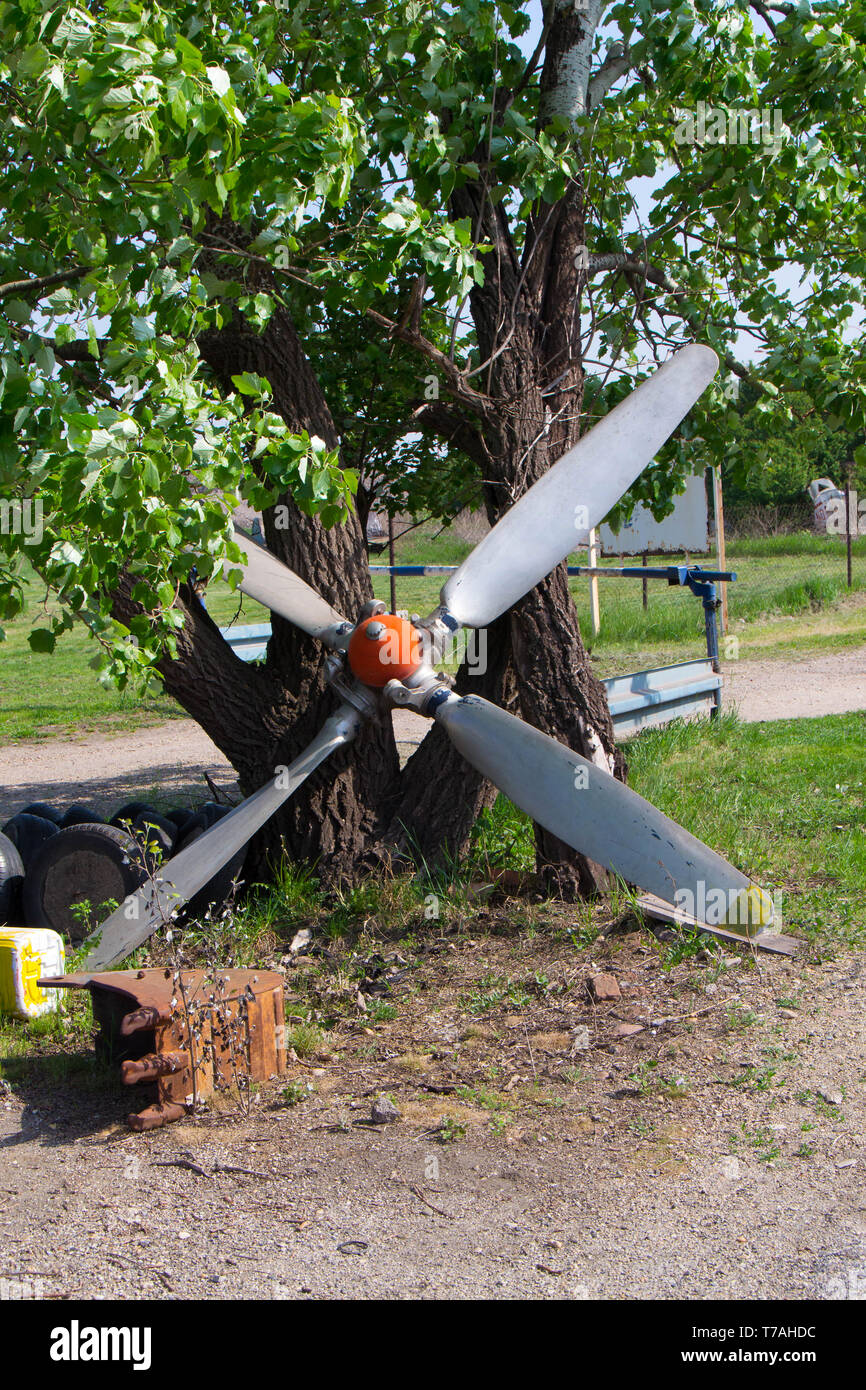 A propeller from a plane leaning against a tree closeup image Stock
