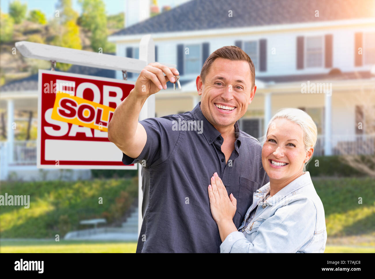 Happy Couple With New House Keys In Front of Sold Real Estate Sign and ...