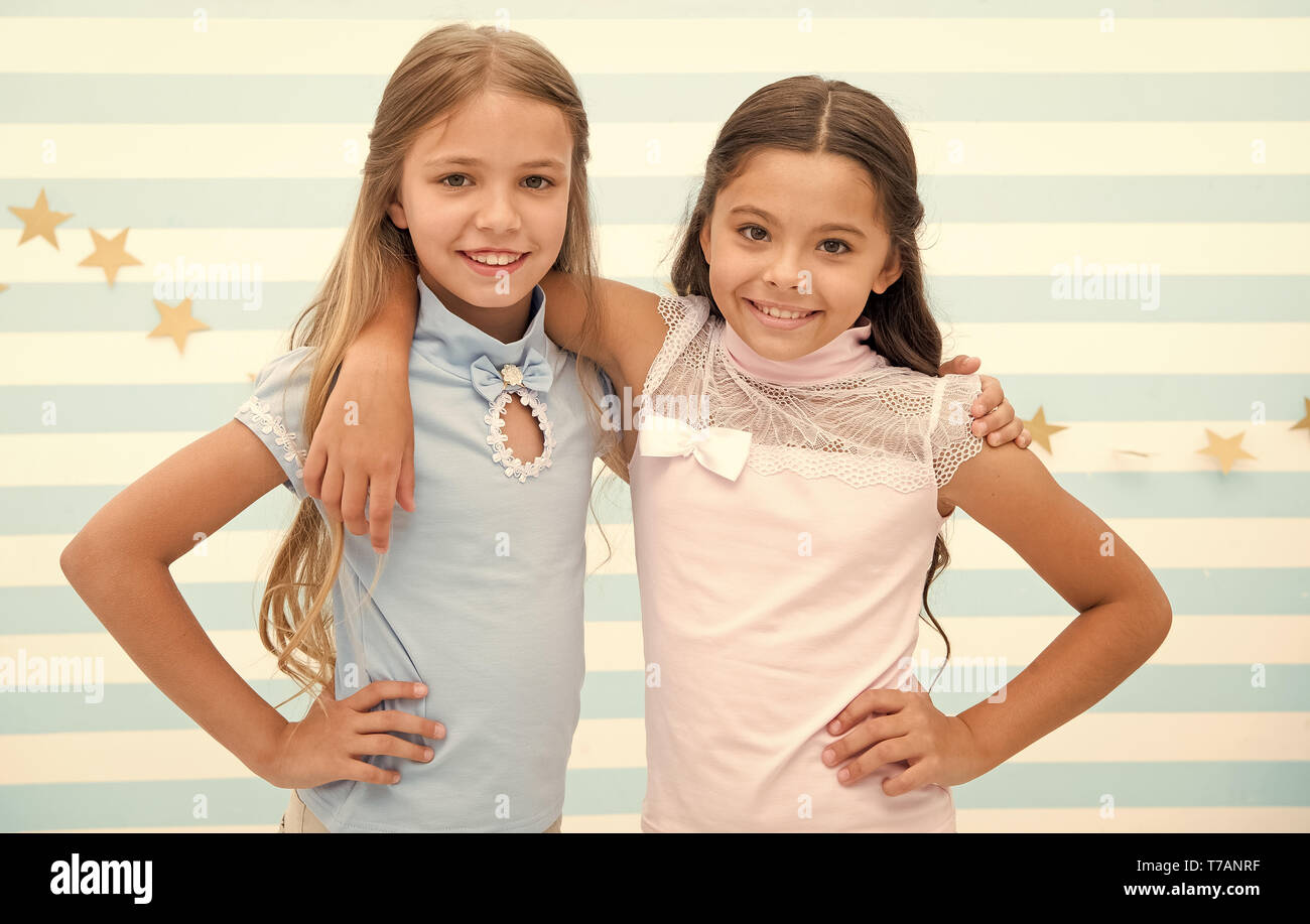Friendship as treasure concept. Kids schoolgirls preteens happy together. Friendship from childhood. Girls smiling happy faces hug each other stand striped background. Girls children best friends hug. Stock Photo