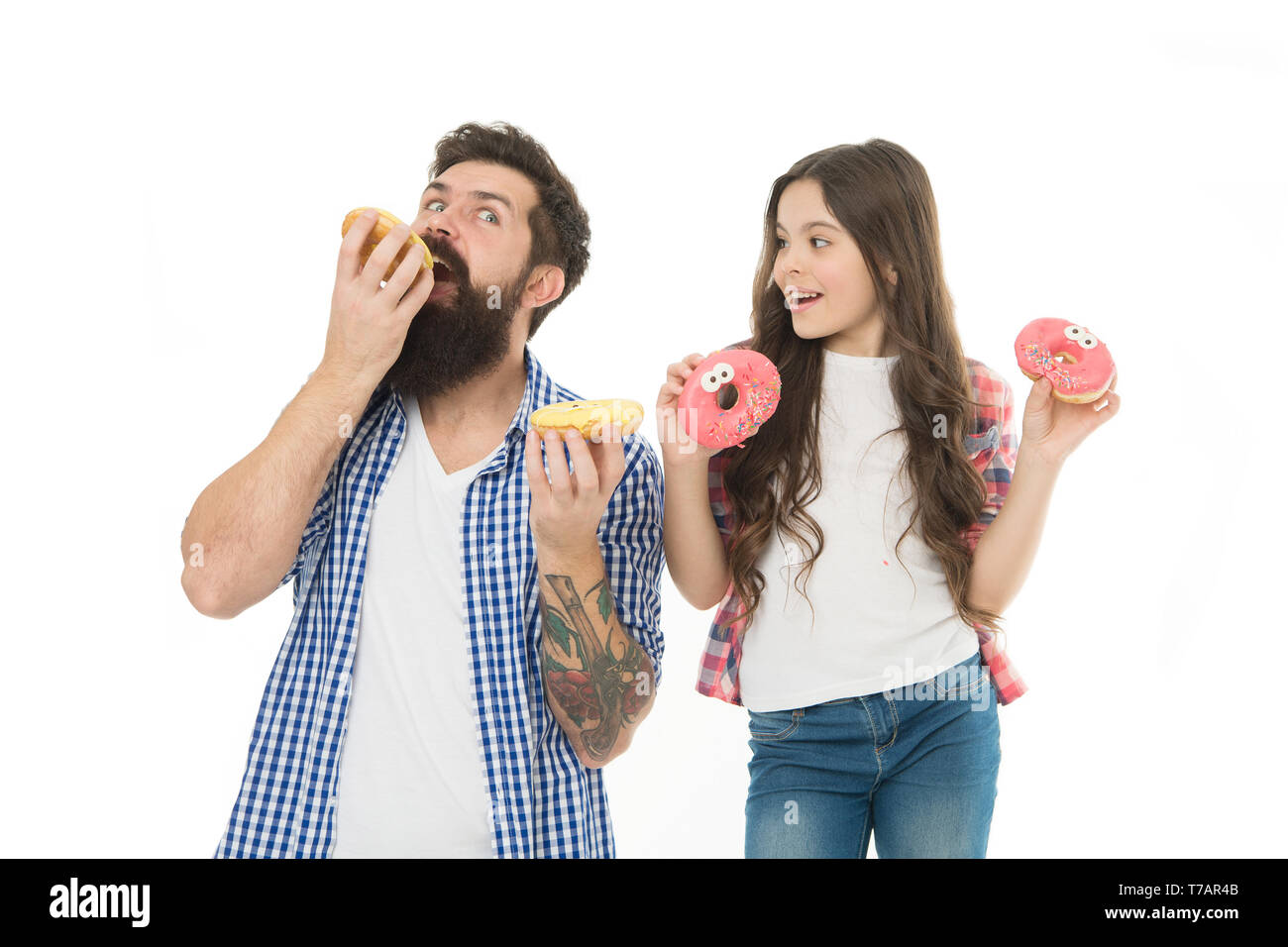 We have passion for tasty doughnuts. Father and small daughter eating glazed doughnuts. Bearded man and little girl child holding ring doughnuts. Hipster and cute kid with fried doughnuts in hands. Stock Photo