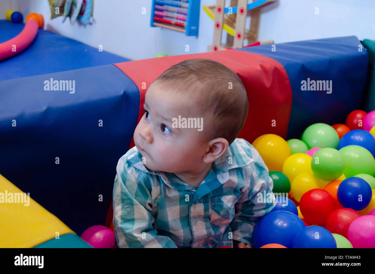 Cute six months old baby boy playing with colorful balls in the