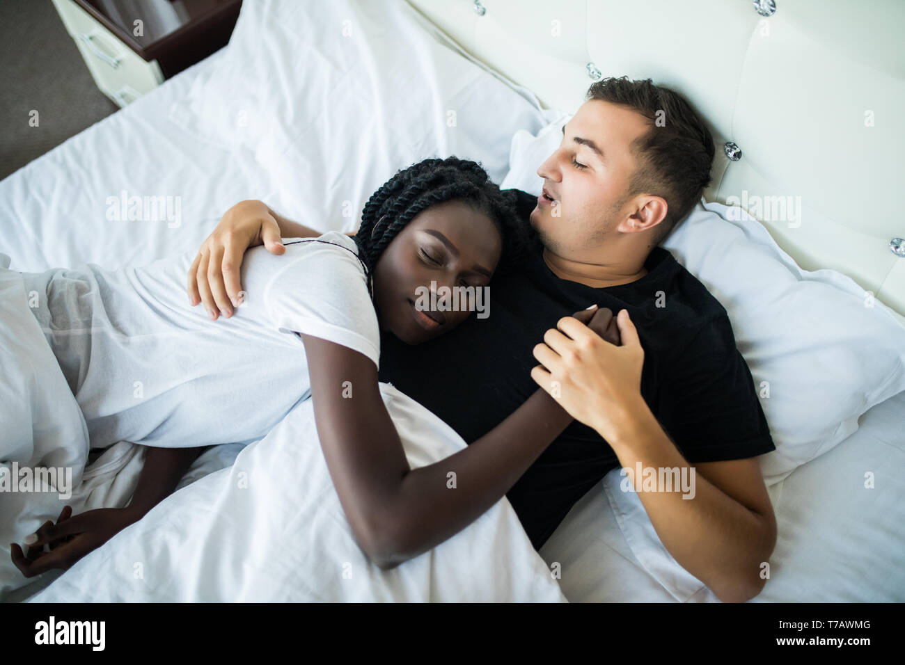 Young loving couple sleeping in bed, they are hugging, top view ...