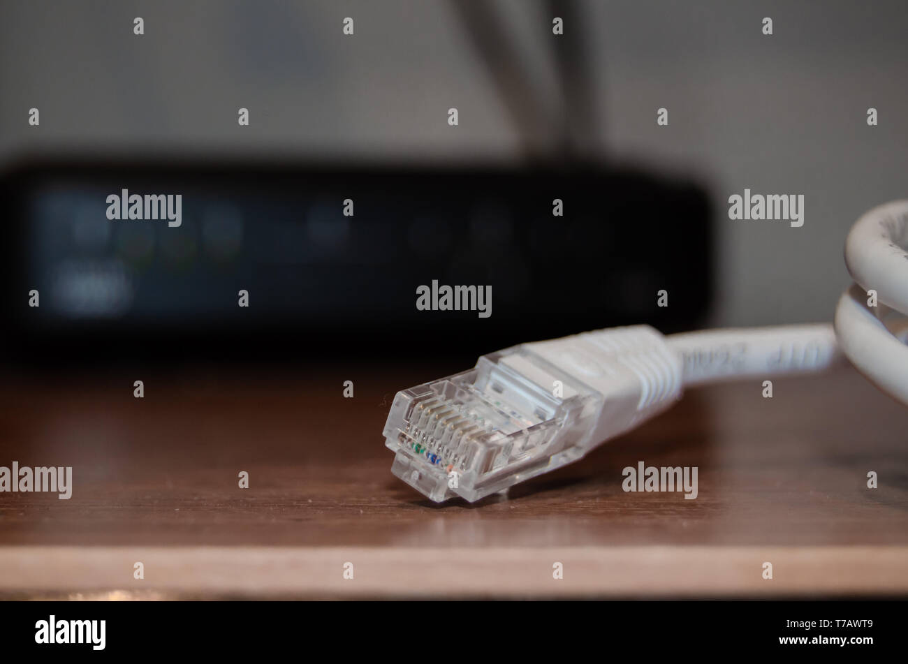 Close up of internet cable on wooden table with modem in the background ...