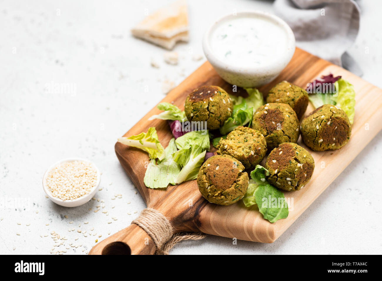 Falafel with yogurt sauce and green salad leaf on wooden serving board. Selective focus. Copy space Stock Photo