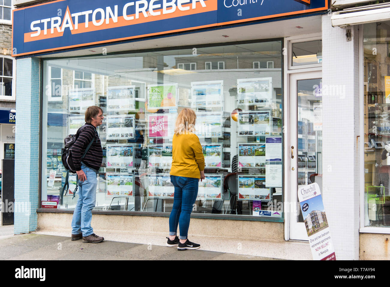 People looking at property information in a Stratton Creber Estate Agent window in Newquay Town Centre in Cornwall. Stock Photo