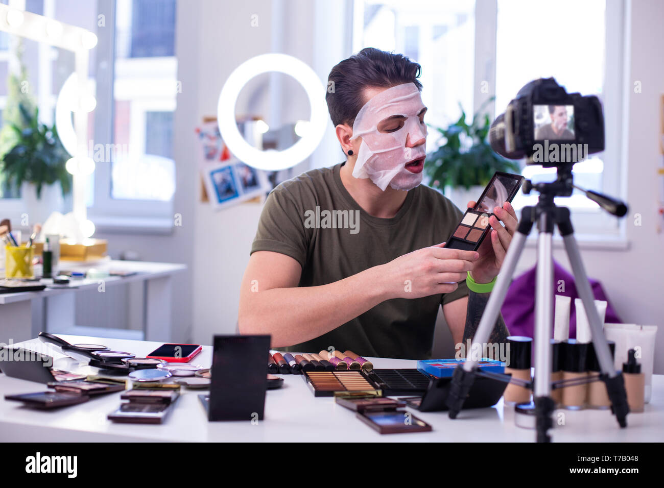 Curious interested man in face mask opening eyeshadow palette Stock Photo