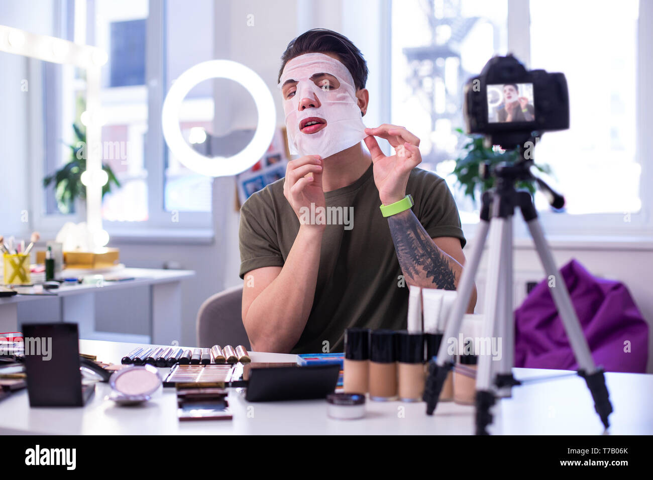 Accurate feminine guy taking off face mask while reviewing it Stock Photo