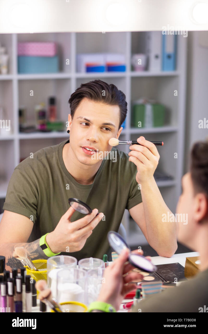 Calm good-looking young man being obsessed with makeup Stock Photo