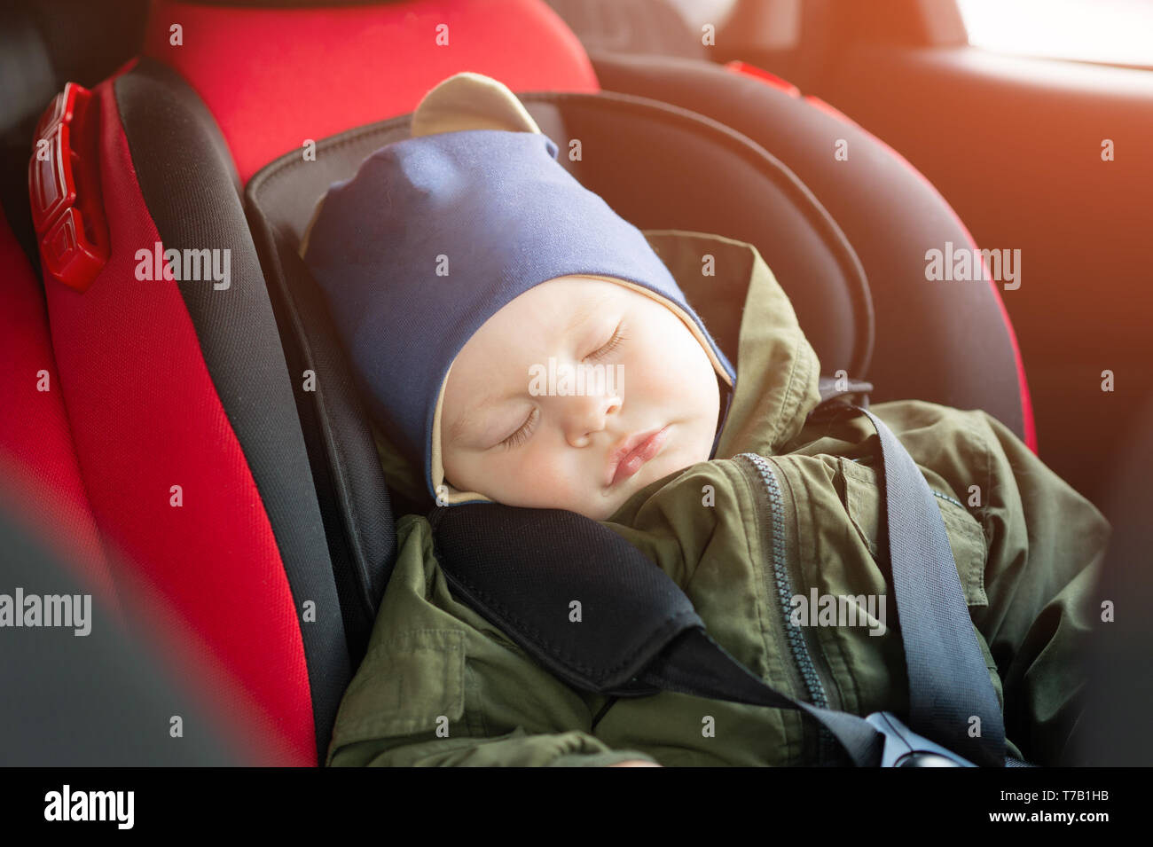 Close Up caucasian cute baby boy sleeping in modern car seat. Child traveling safety on the road. Safe way to travel fastened seat belts in a vehicle  Stock Photo