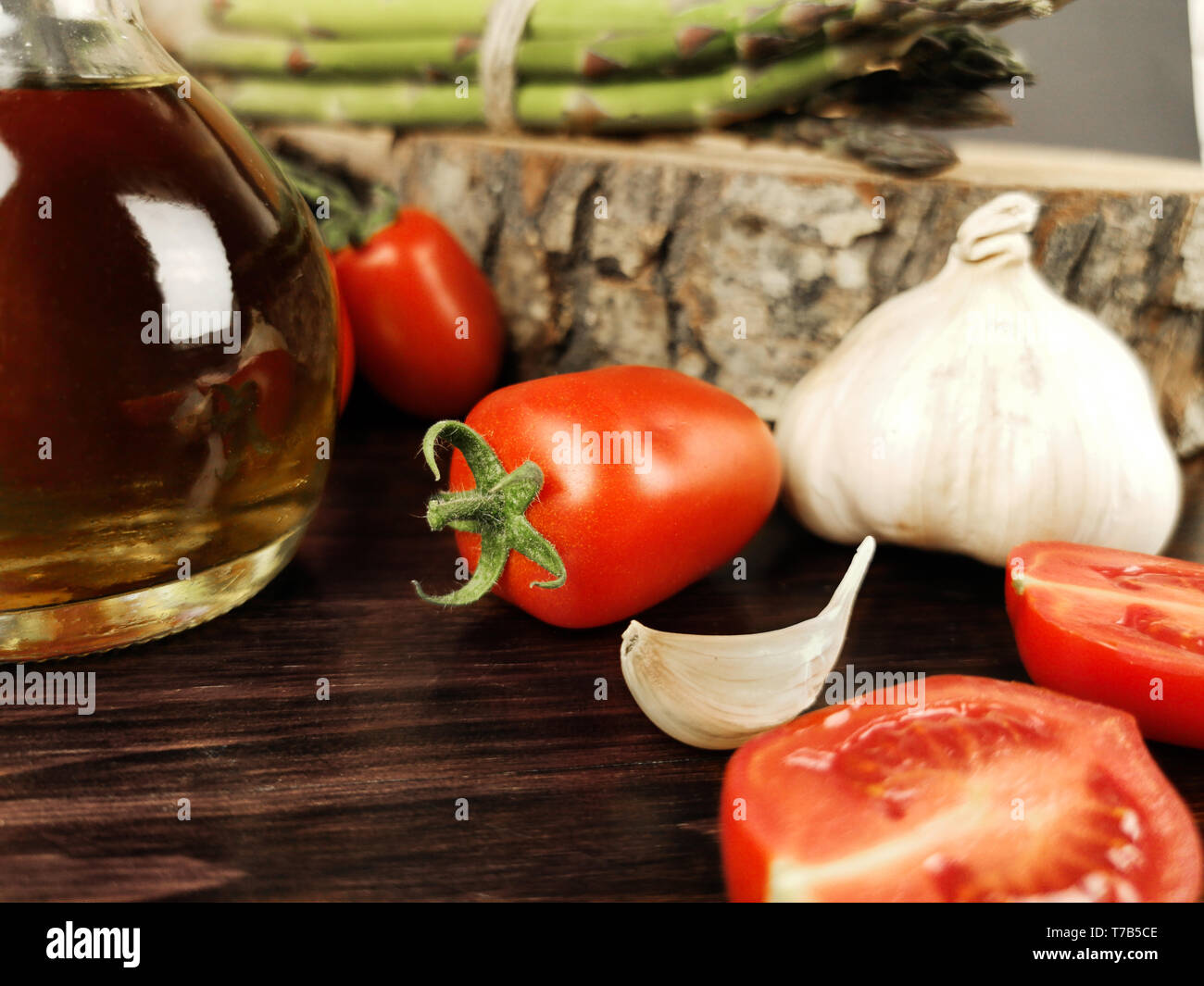 tomatoes, olive oil, asparagus and garlic on dark wood table Stock Photo
