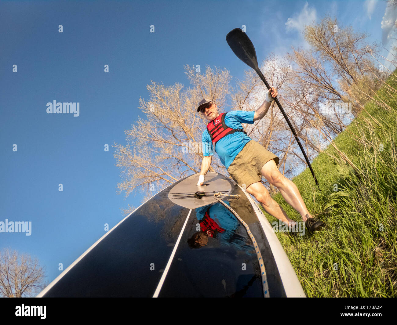 senior paddler wearing inflatable life jacket and paddling gloves is