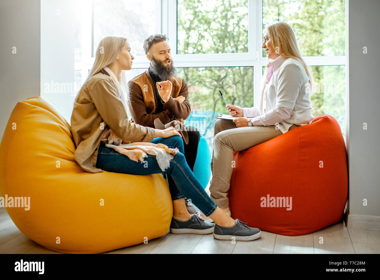Young couple having misunderstandings during the psychological counseling with senior female psychologist in the office Stock Photo