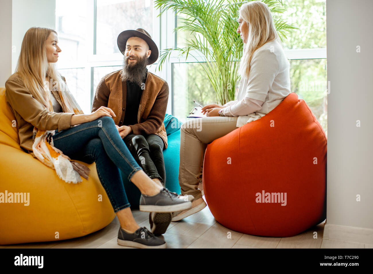Young happy couple during the psychological counseling with senior female psychologist or mental coach on the comfortable chairs in the office Stock Photo