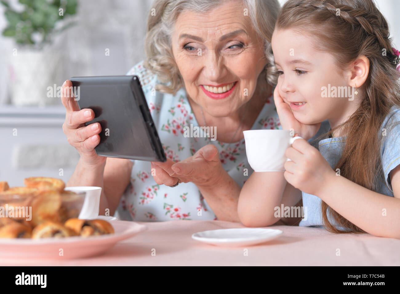 Cute little girl with her grandmother looking at tablet Stock Photo - Alamy