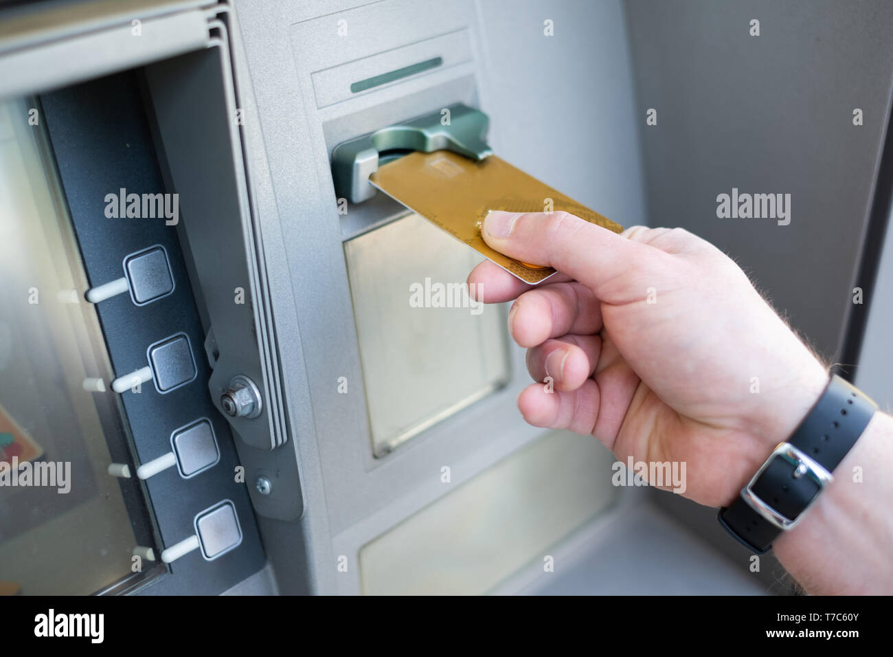 Close up of one hand inserting ATM credit card into bank machine to withdraw money Stock Photo
