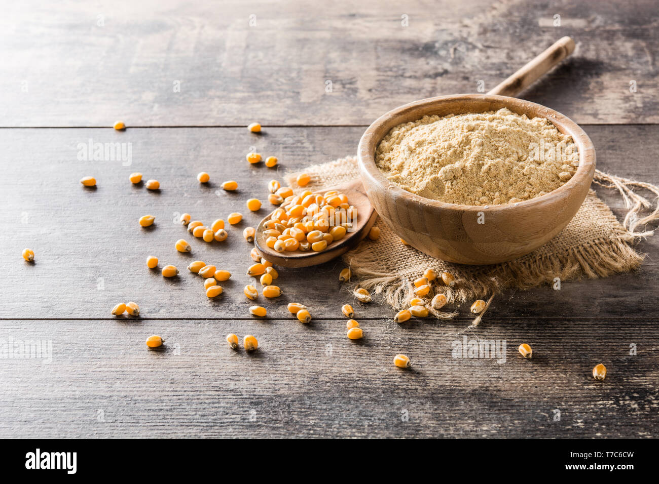 Corn flour in bowl on wooden table Stock Photo