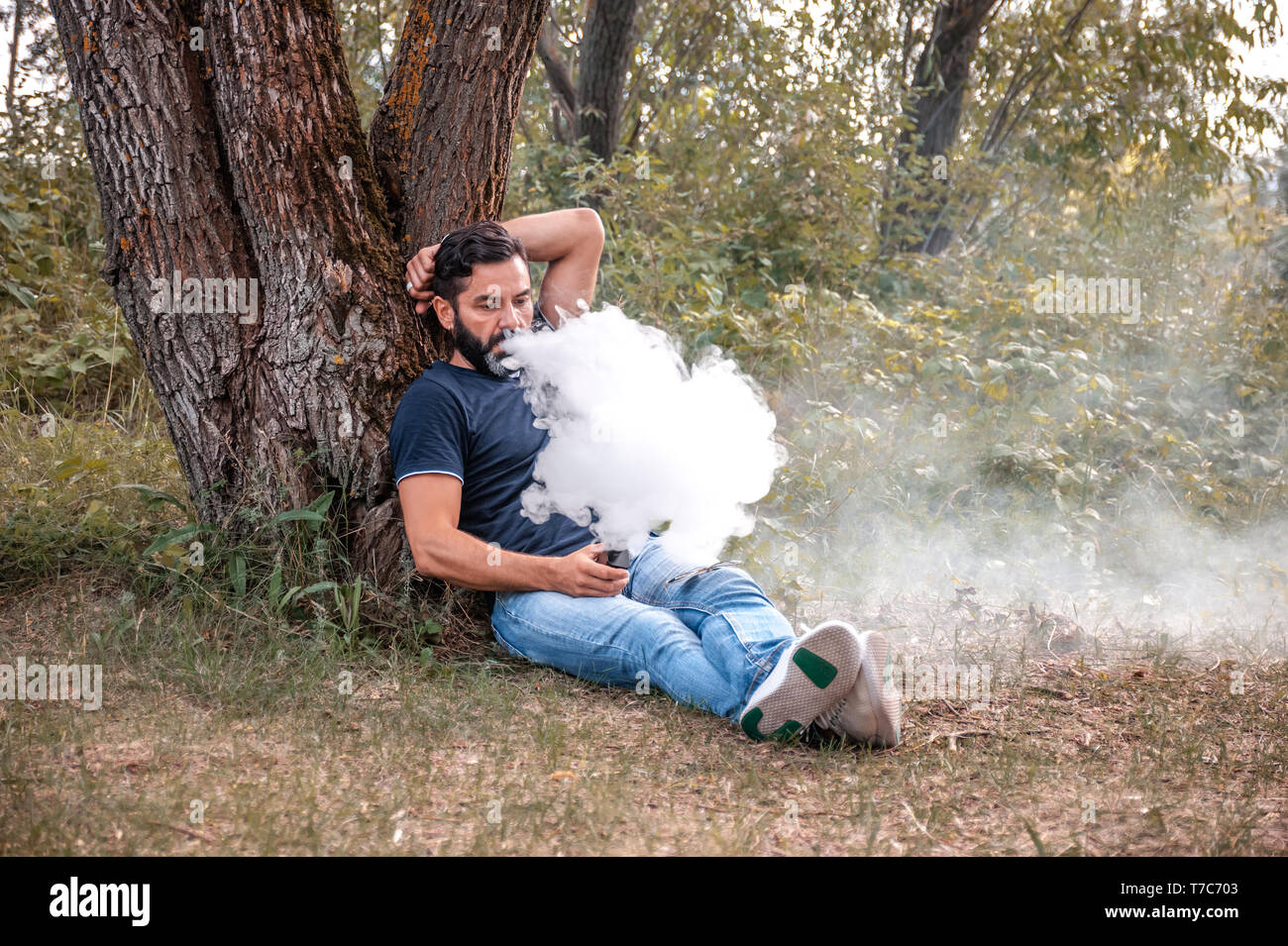 Bearded vape man in the fresh air smoking an electronic cigarette.  Alternative to smoking Stock Photo