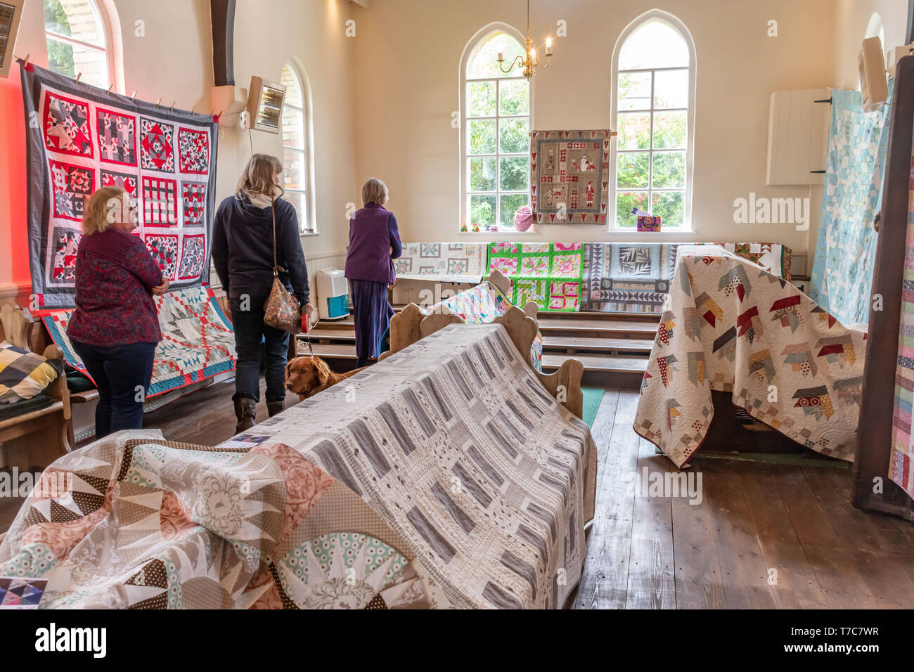 Homemade quilts on display in a village hall at the Oakhanger May Fayre in Hampshire, UK. Craft exhibition, sewing, needlework, handicrafts. Stock Photo