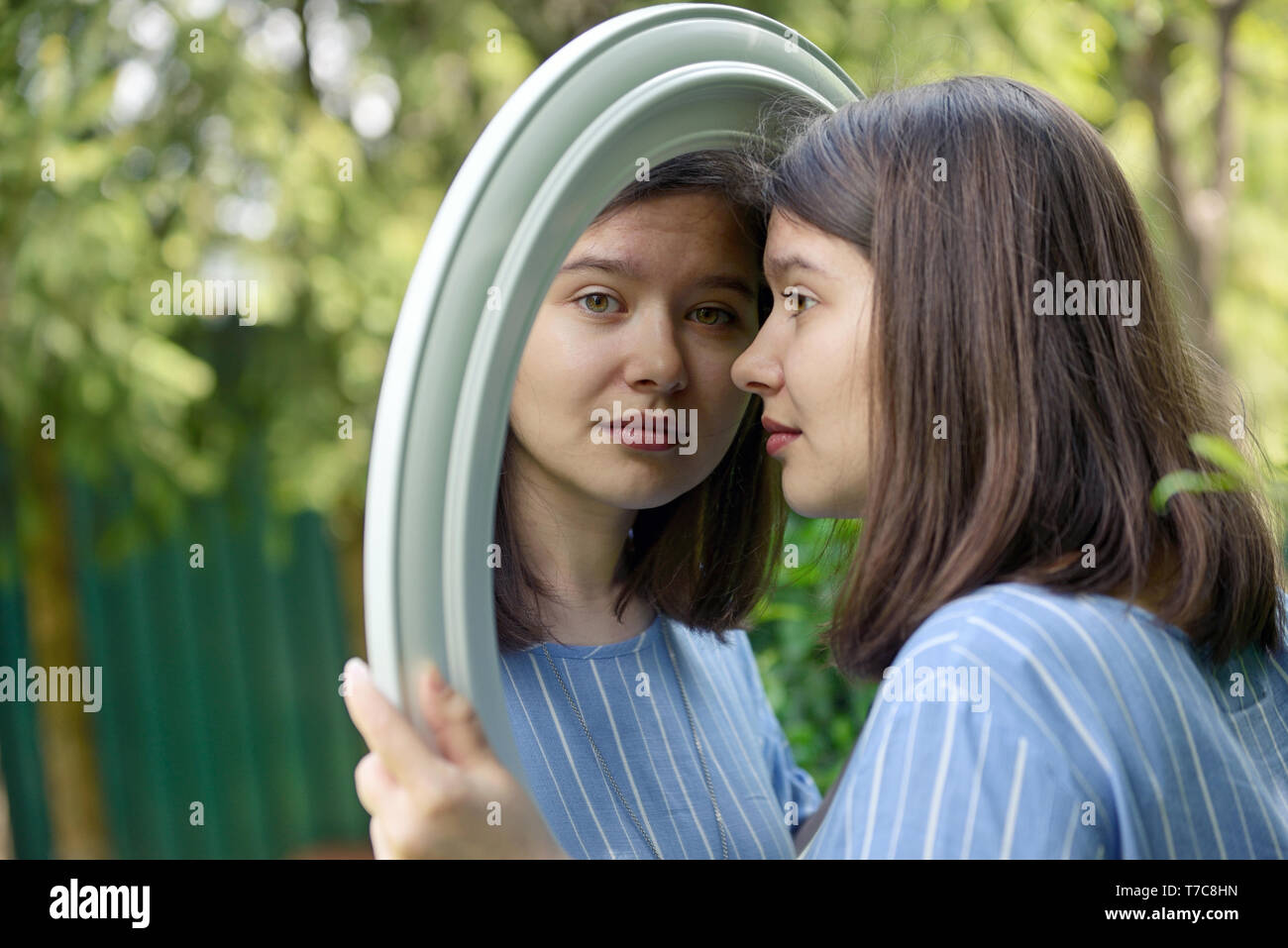 Girl looking in mirror with nature background Stock Photo