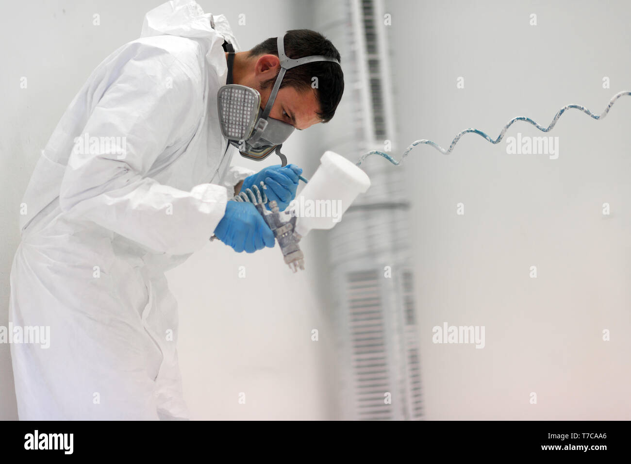 Painter using airbrush to paint wearing protective clothing Stock Photo