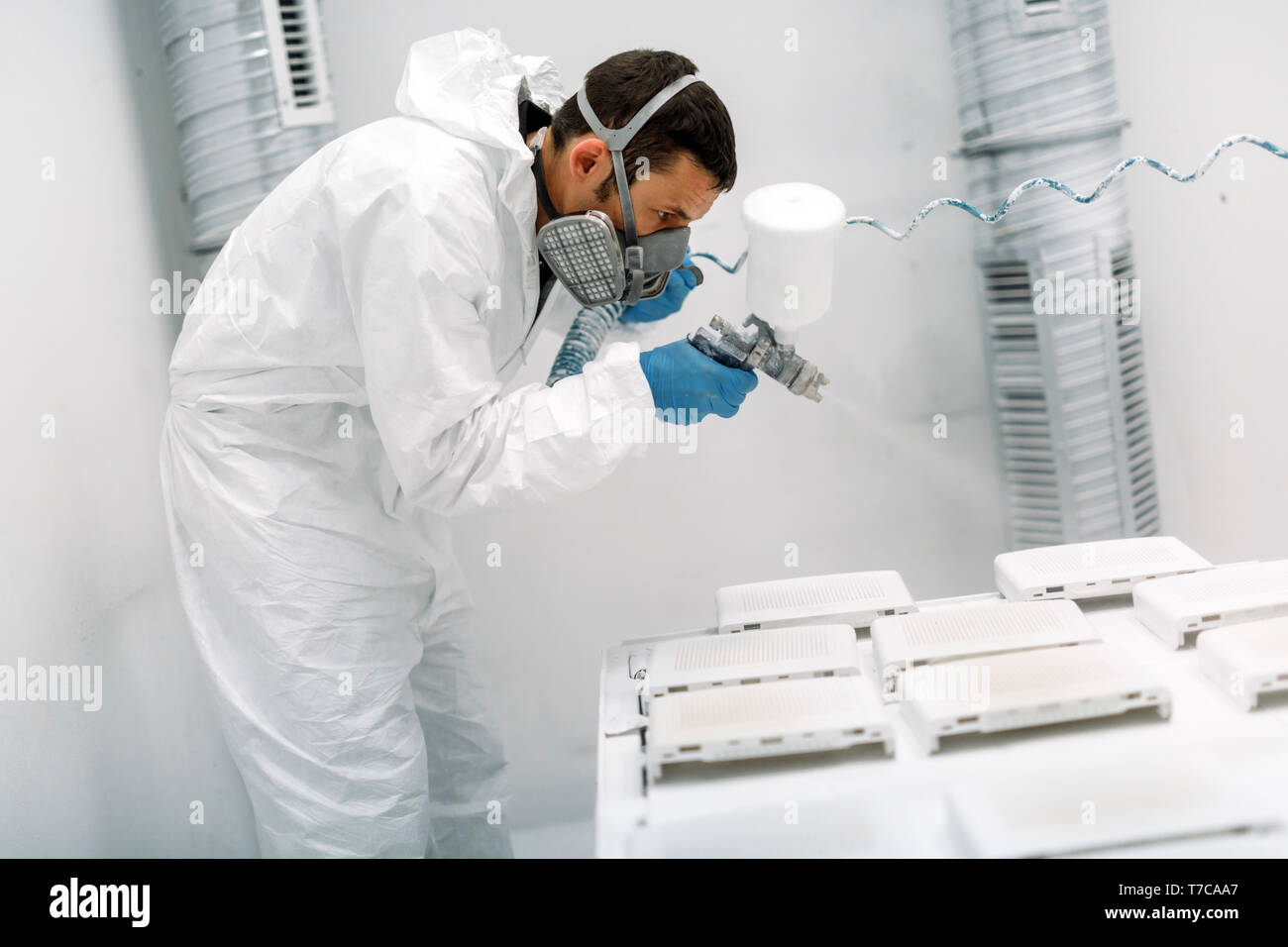 Painter using airbrush to paint wearing protective clothing Stock Photo