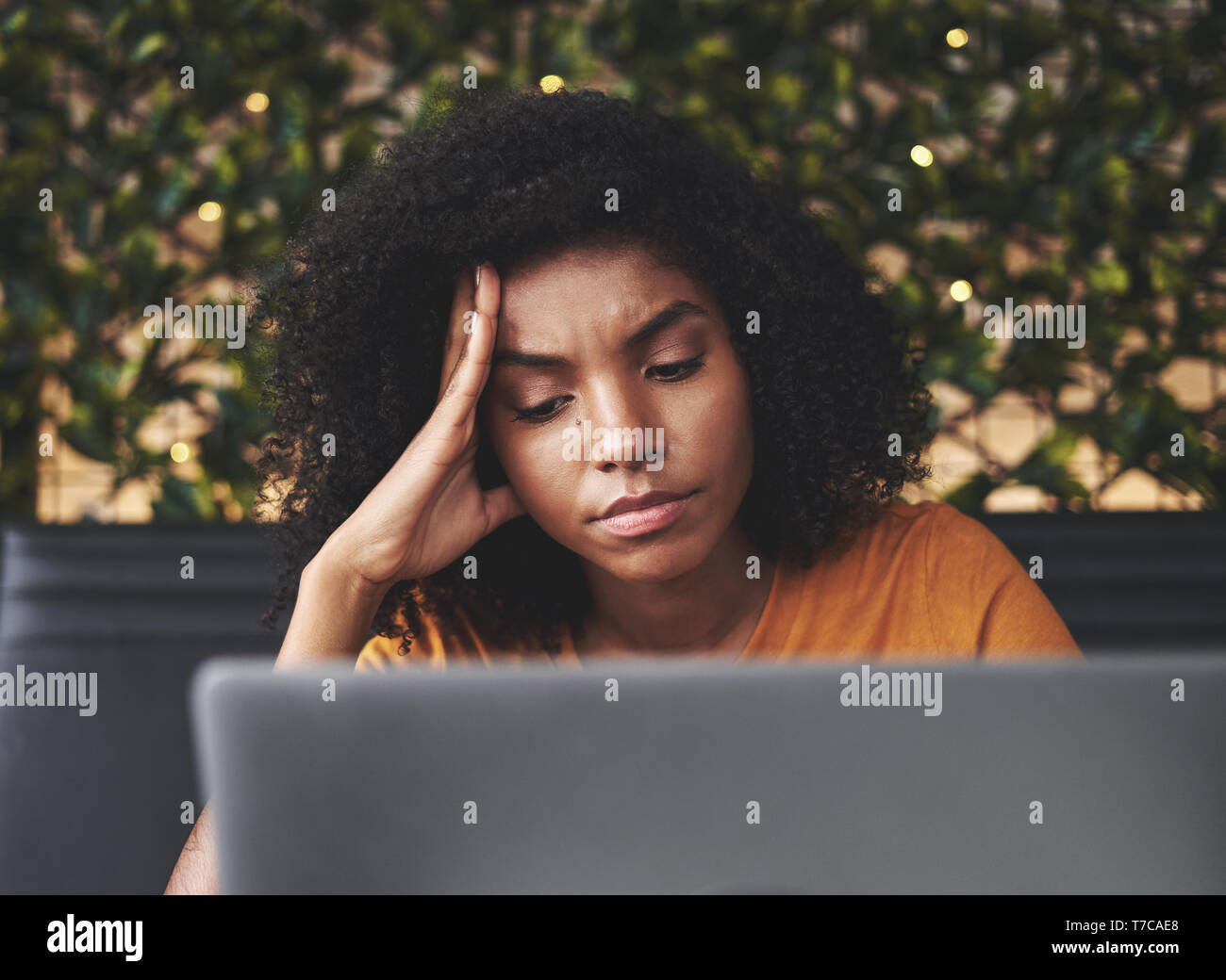 Worried young woman looking at laptop in cafe Stock Photo