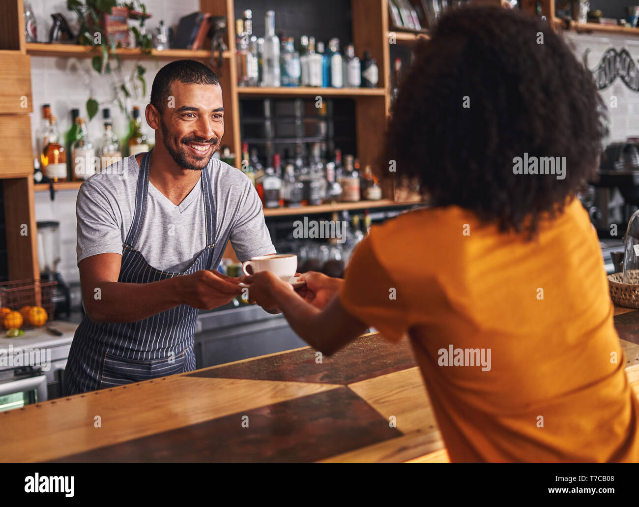 Male barista serves coffee cup to female customer in cafe Stock Photo