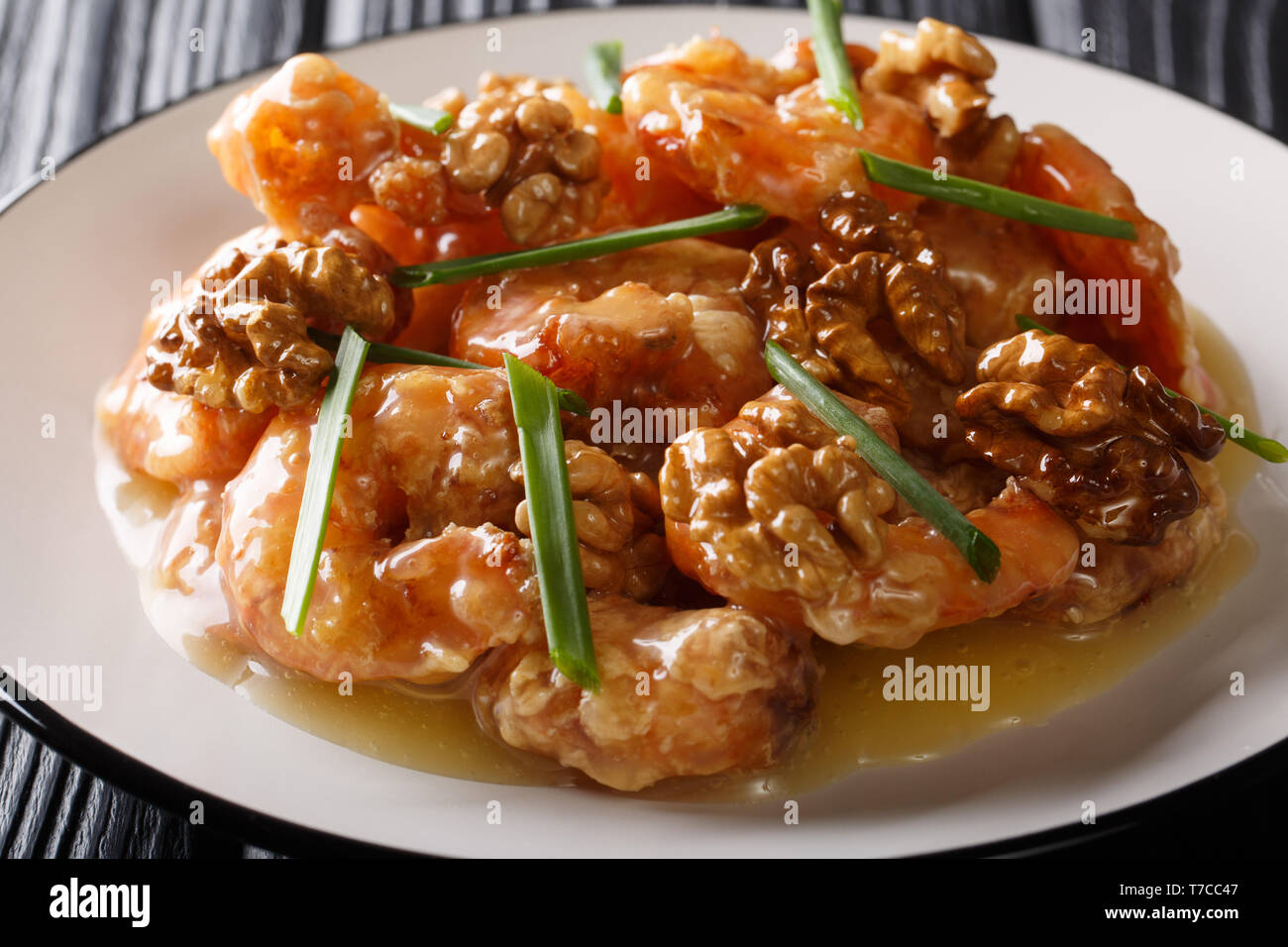 Crispy shrimp tossed in a creamy sweet sauce and candied walnuts close-up on a plate. horizontal Stock Photo