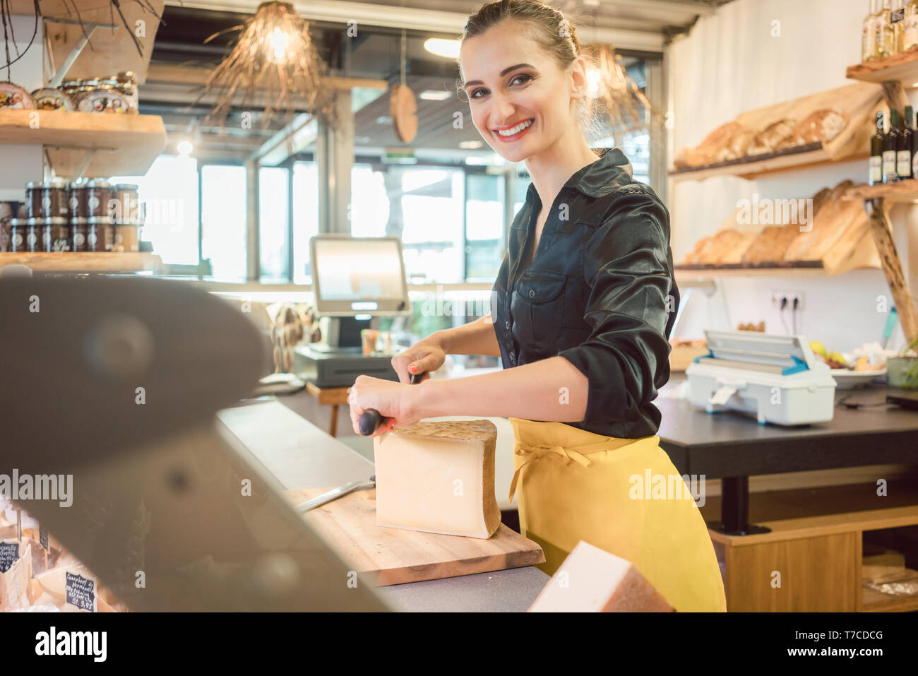 Shop clerk in deli cutting cheese Stock Photo