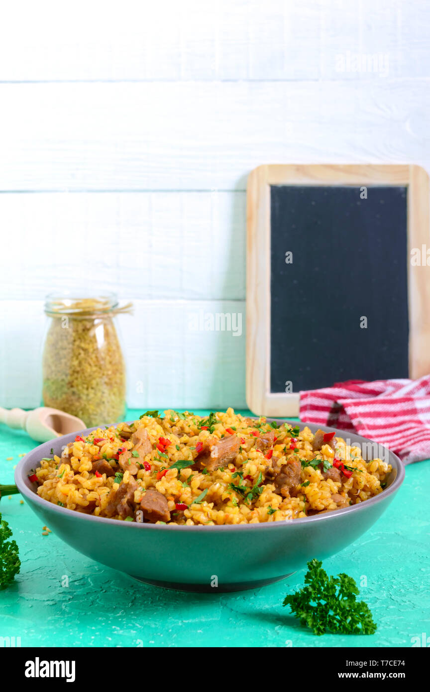 Bulgur with chicken and vegetables. Delicious healthy warm salad on a bright background. Bulgur