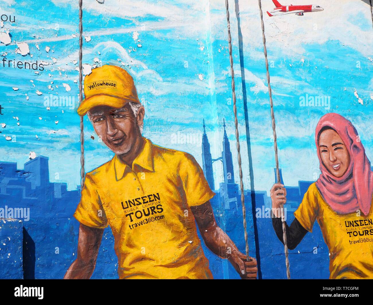 Street art showing a muslim couple in yellow clothes on a swing in front of the Petronas Towers in Malaysia. Street art found in George Town / Penang. Stock Photo