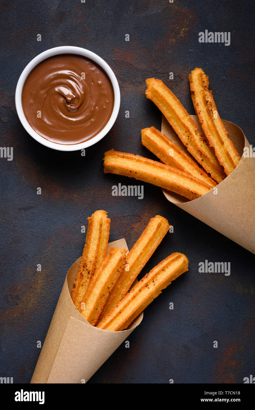 Churros with cinnamon and chocolate sauce on dark background flat lay top view Stock Photo