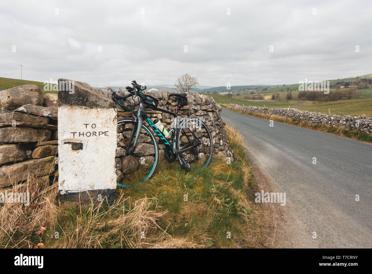 Quaint signpost to Thorpe with a pointing finger and a road bike leaned