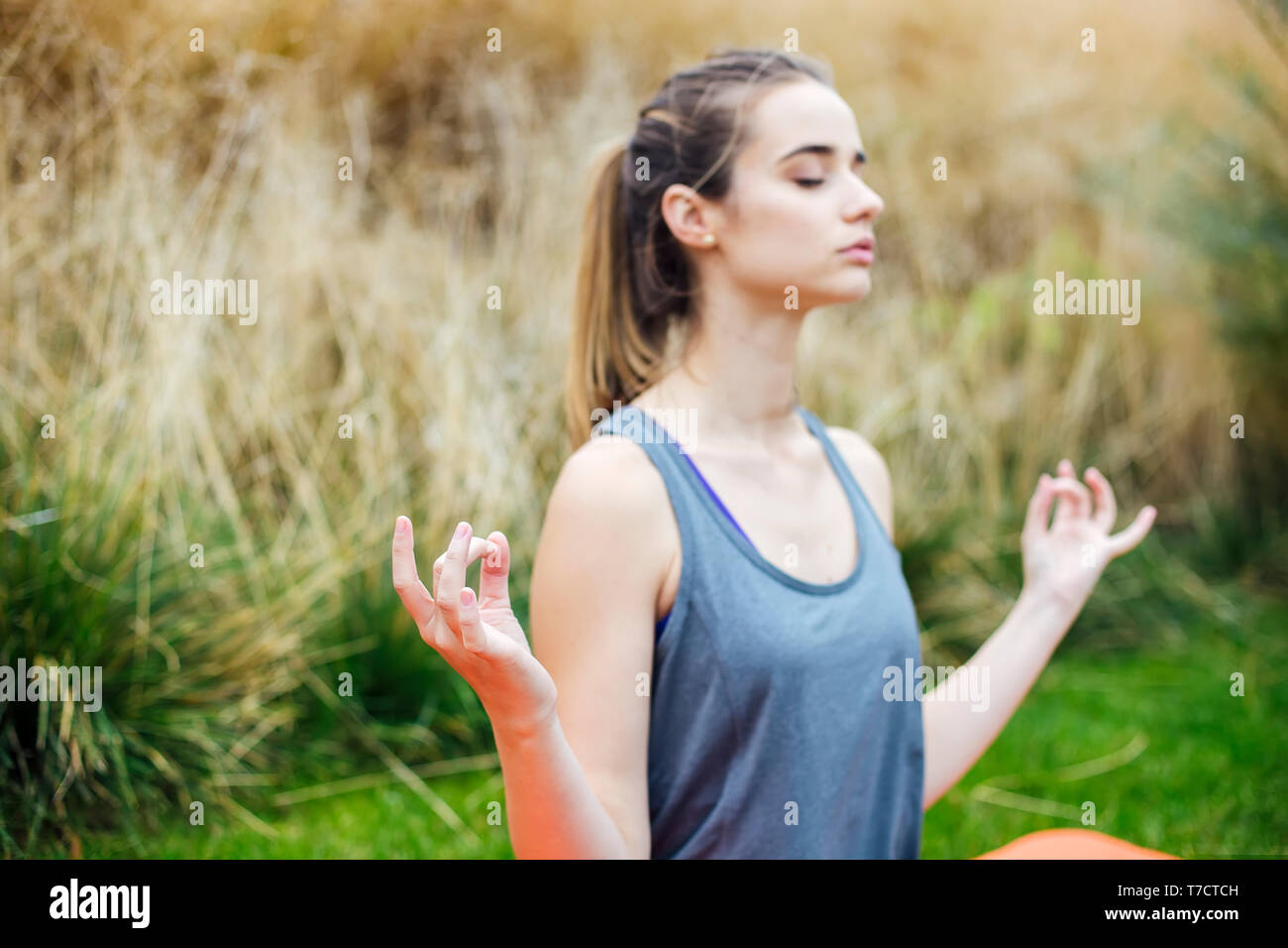 Pretty young woman practices yoga and meditates in the lotus position ...