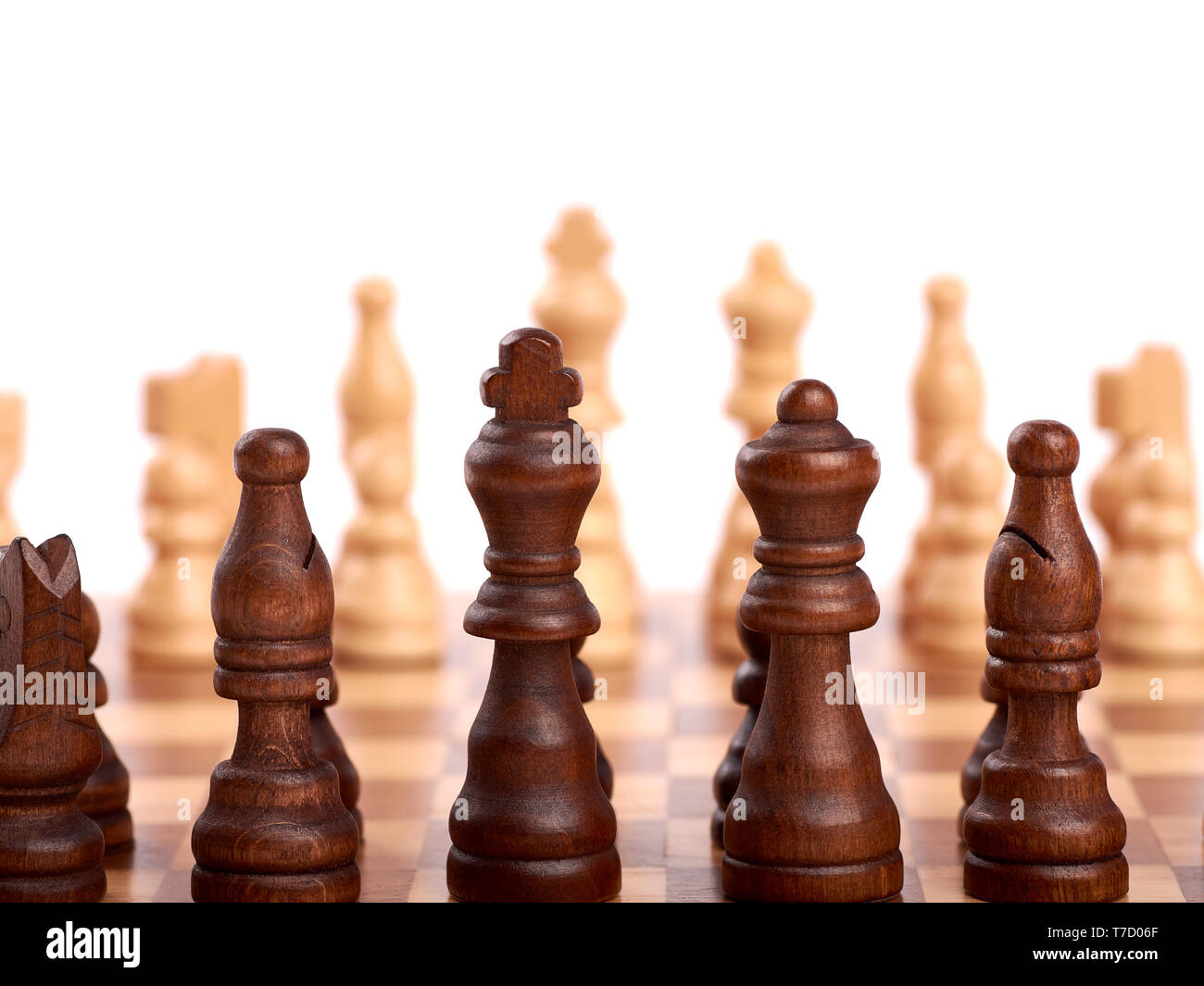 Wooden chess pieces in a duel on a chessboard. King, lady and shooter with horse. Out of focus team of enemies. Isolated on white background Stock Photo
