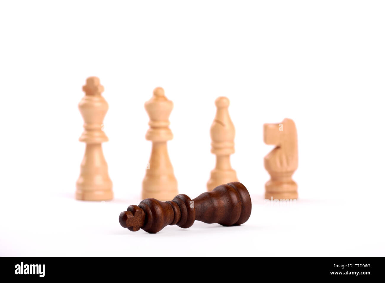 Wooden chess pieces in duel. White king, lady and shooter with horse. The defeated black king surrenders to the enemy team. Isolated on white backgrou Stock Photo