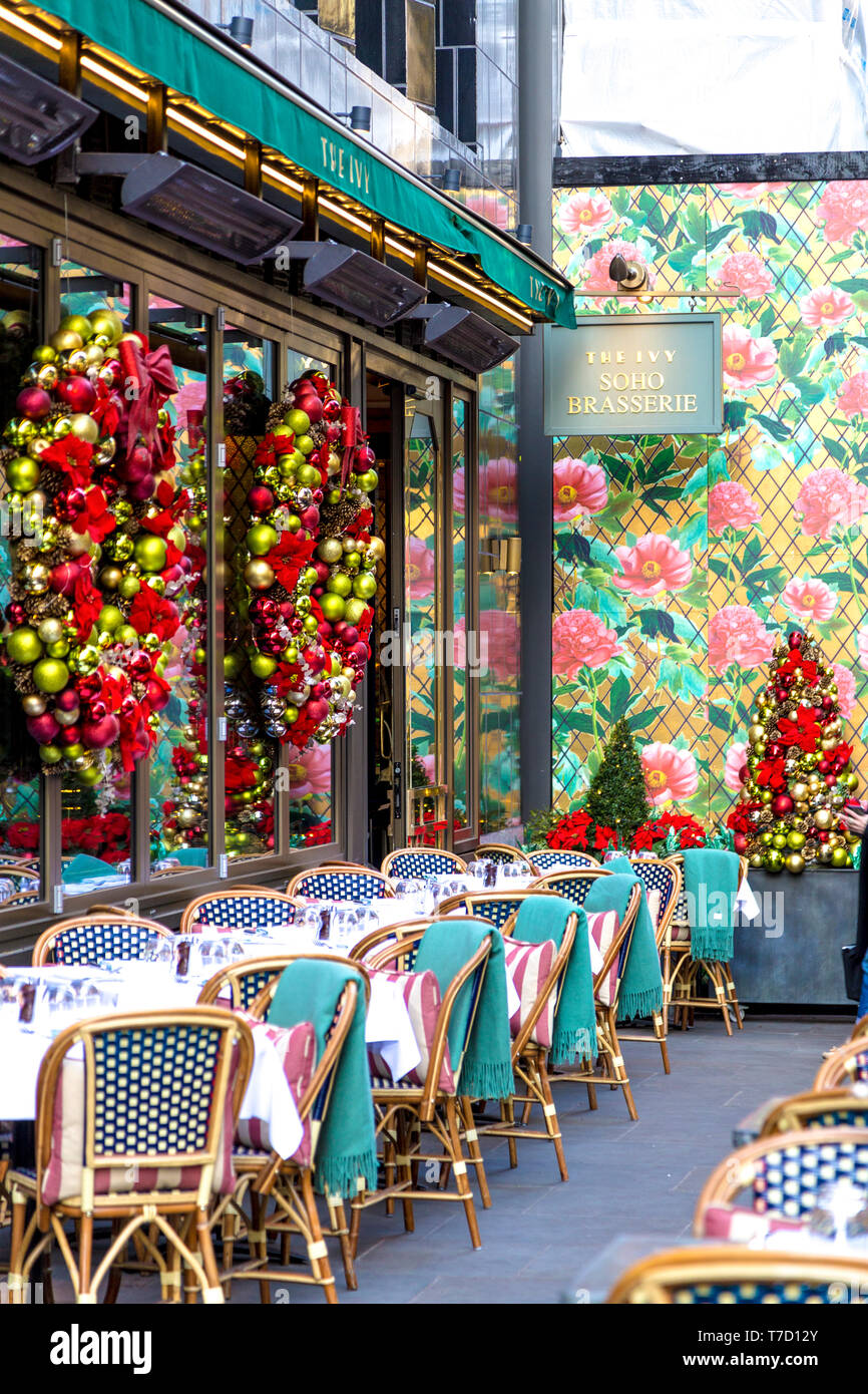 Al fresco tables and chairs at the Ivy Soho Brasserie decorated for Christmas time, London, UK Stock Photo