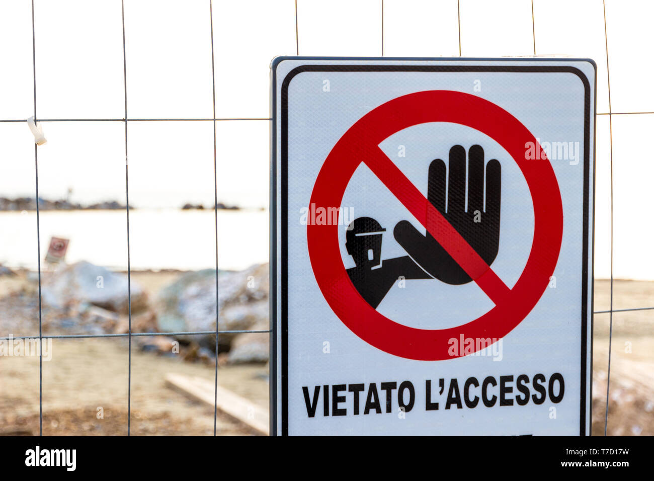Warning sign reading: 'no entry' near a construction site on the shoreline in Follonica, Italy Stock Photo
