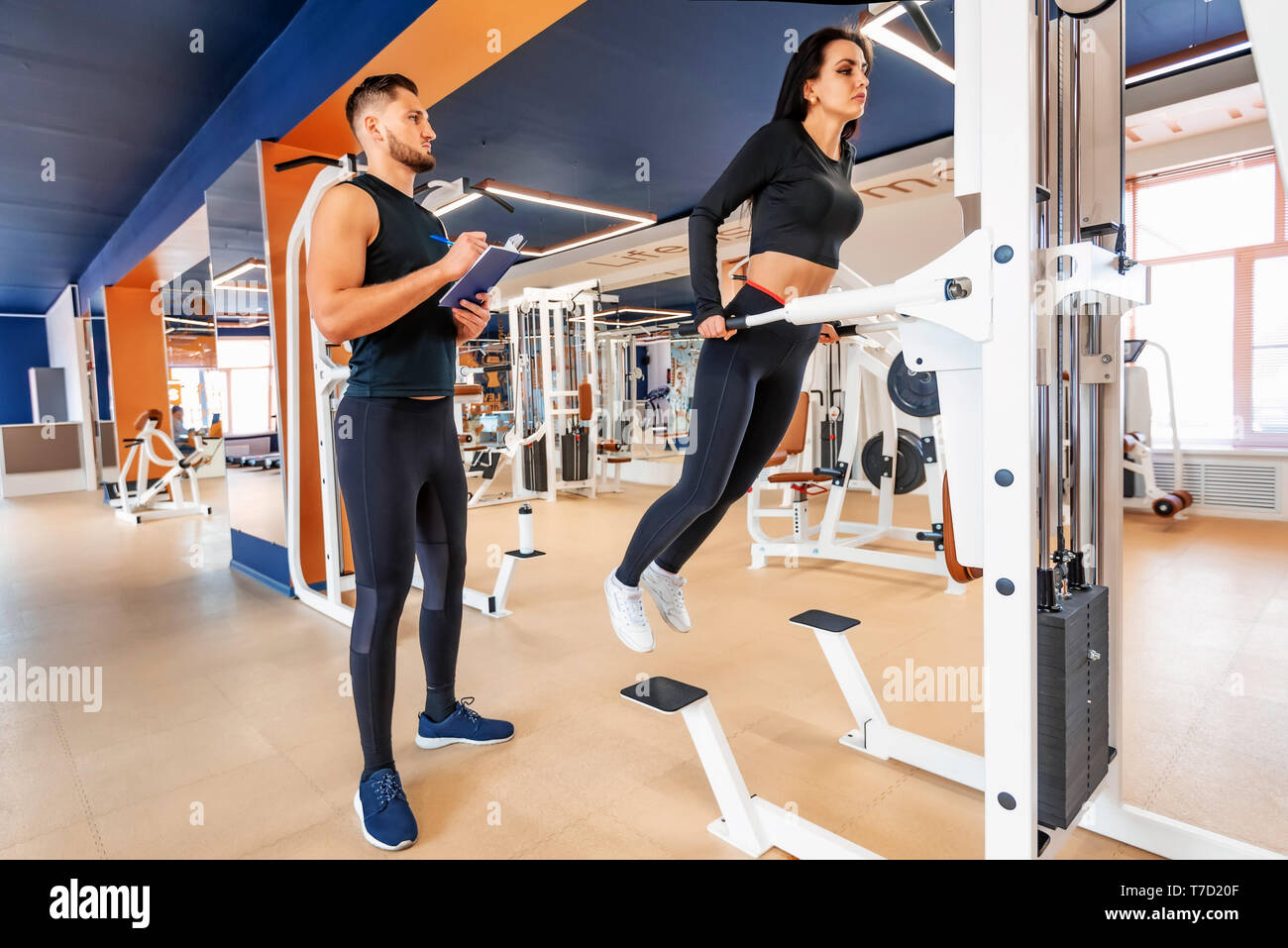 Personal trainer coaching female bodybuilder making dip exercise on machine Stock Photo Alamy