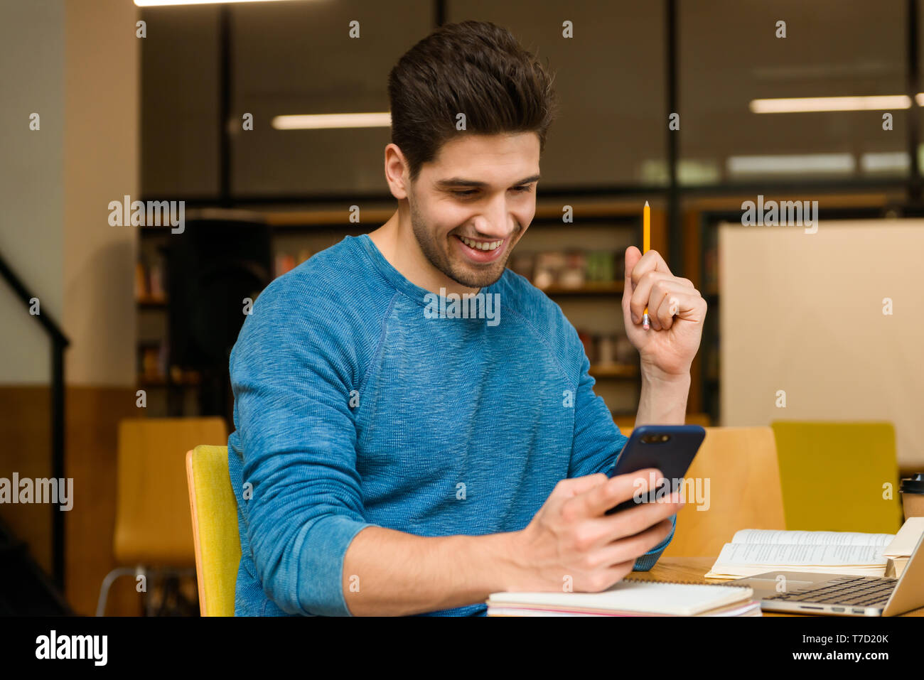 Image of a young student concentrated man in library doing homework ...